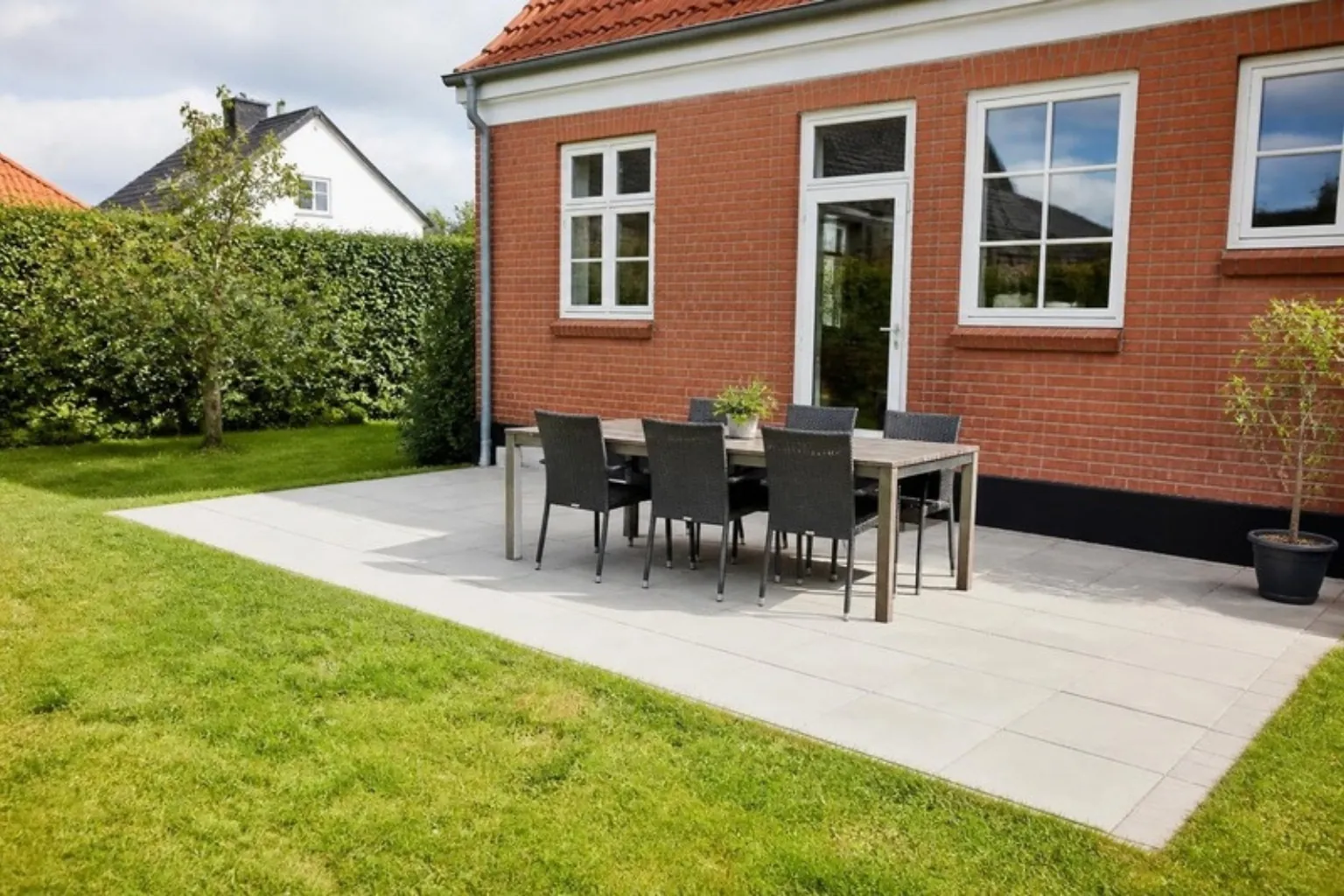 Fliseterrasse med havemøbler ved murstenshus